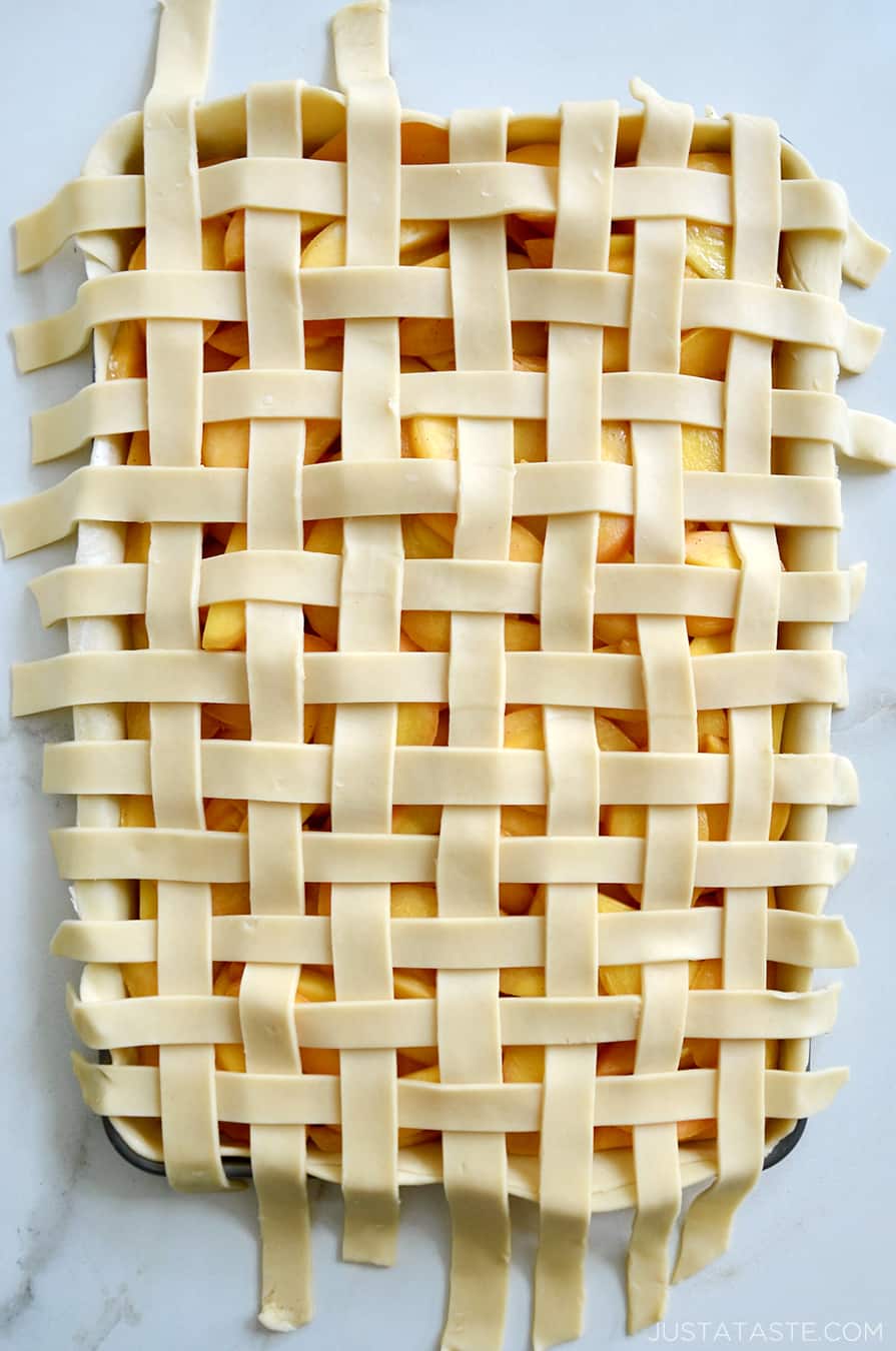 A top-down view of lattice pie crust on a peach slab pie