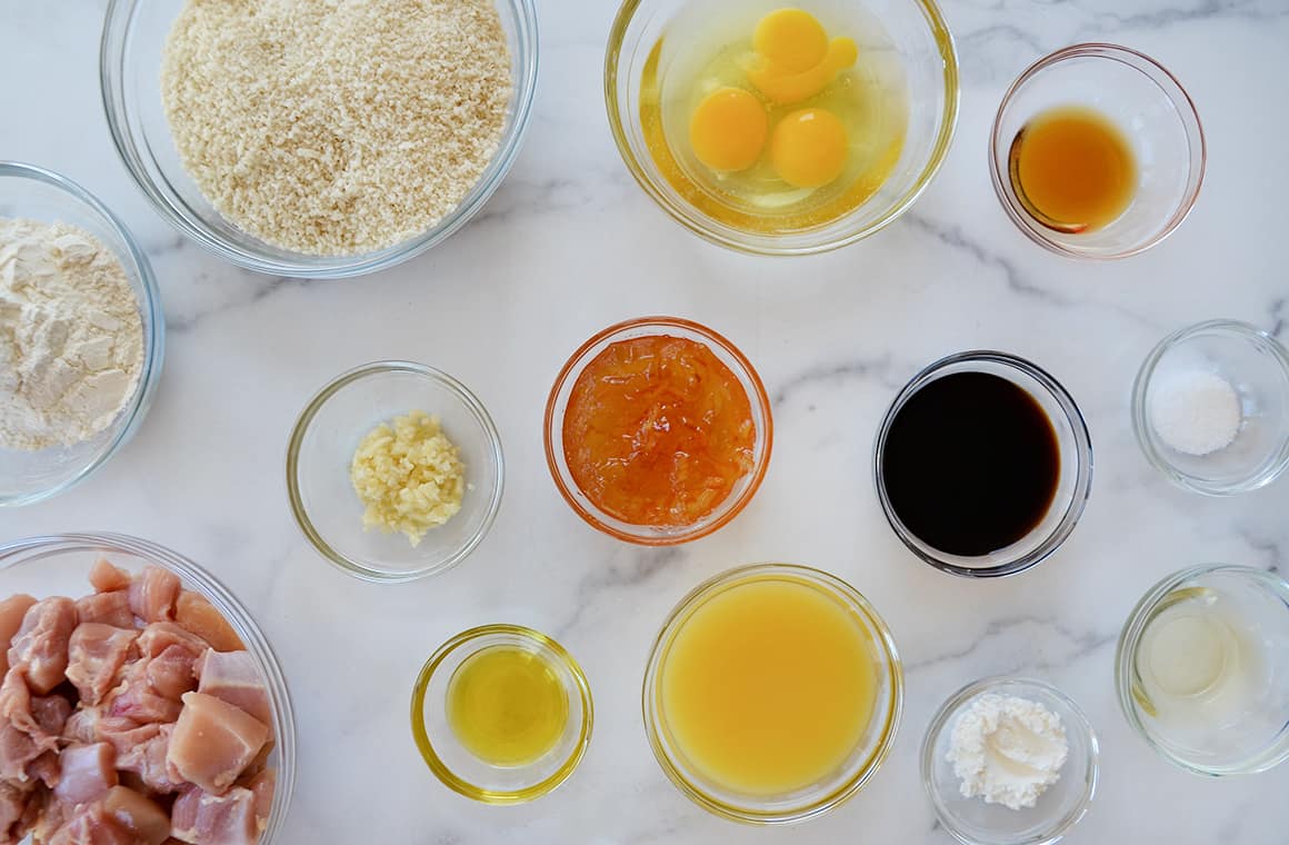 Glass bowls containing ingredients, including chicken thighs, orange juice and soy sauce