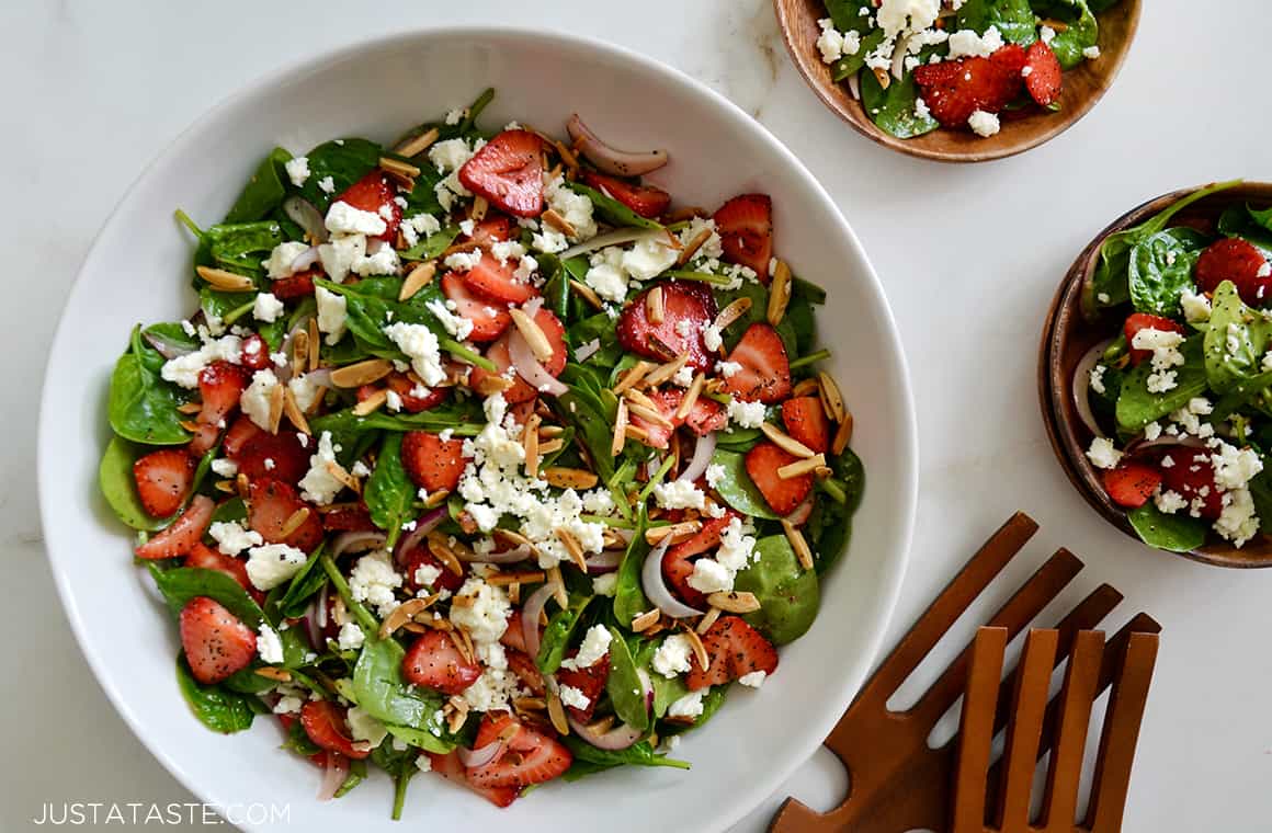 A white bowl containing spinach salad with strawberries