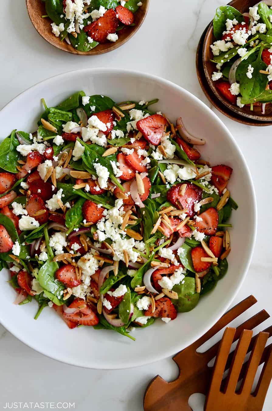 A top down view of a white bowl containing Spinach Strawberry Salad with Poppy Seed Dressing