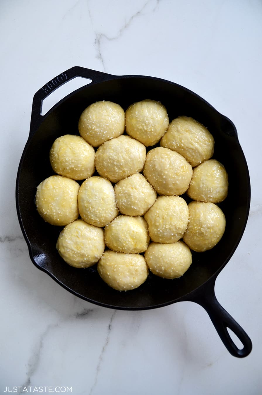 Unbaked pretzel rolls nestled in a greased cast-iron skillet