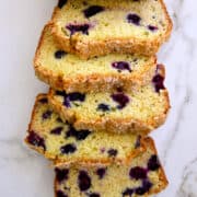 A top-down view of a loaf of Blueberry Orange Juice Bread that's been sliced into five servings above text that reads, "Blueberry Orange Juice Bread" and the Just a Taste purple logo.