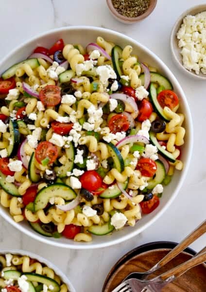 Greek pasta salad with feta, tomatoes, cucumbers and olives in a large serving bowl.