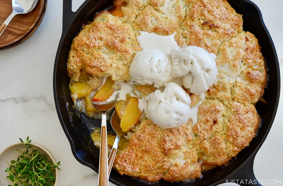 Peach cobbler in a cast-iron skillet with melting ice cream on top