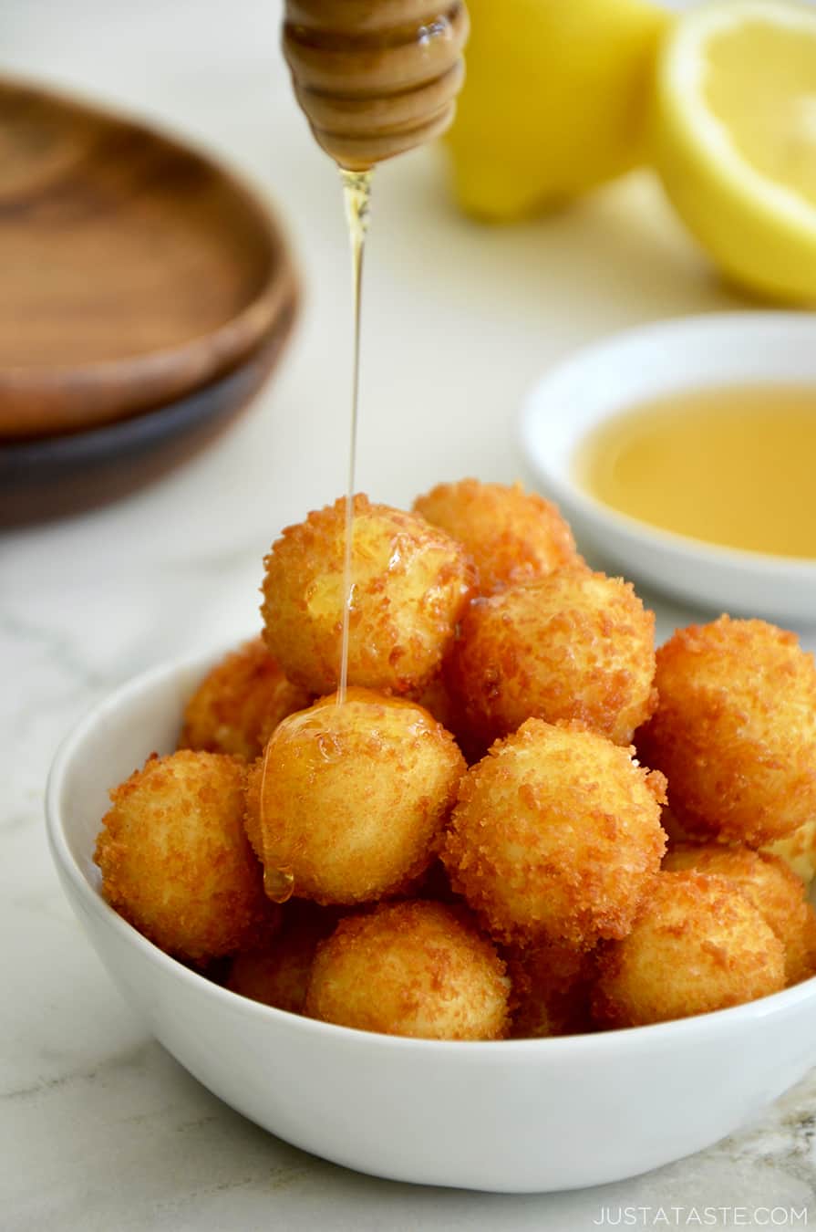 A white bowl containing fried goat cheese balls with honey drizzled on top