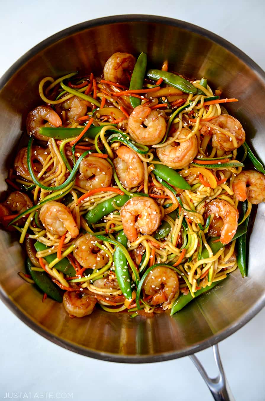 A top-down view of a skillet containing shrimp and vegetables