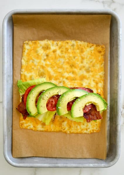 A top-down view of melted cheese sandwich wrap filled with turkey, bacon, avocado, lettuce and tomato