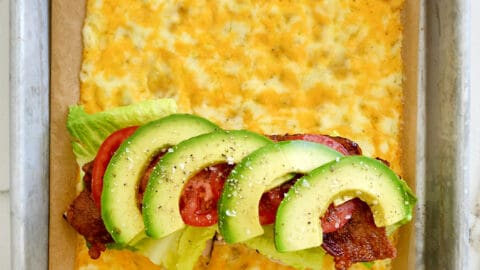 A top-down view of melted cheese sandwich wrap filled with turkey, bacon, avocado, lettuce and tomato