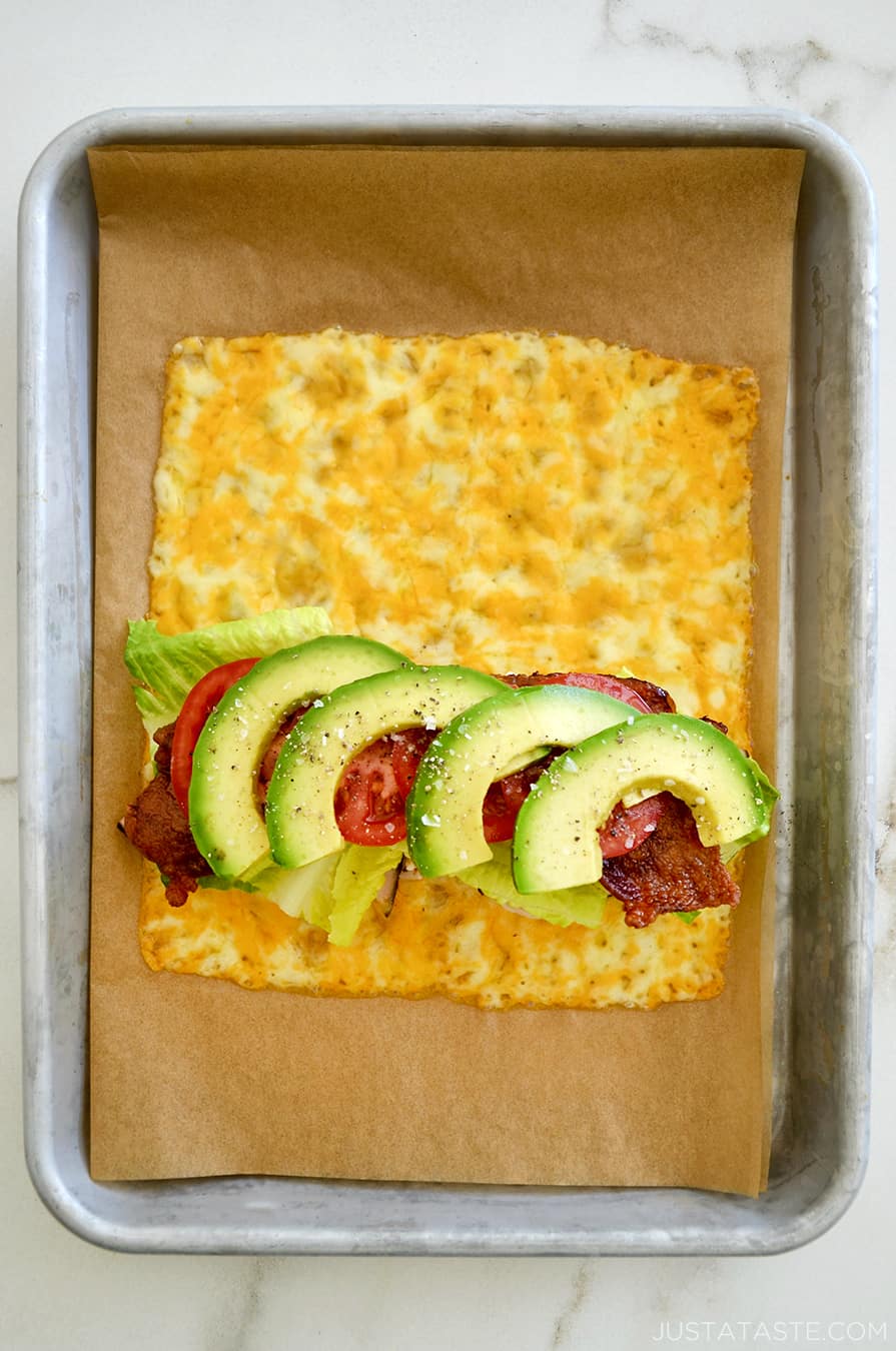 A top-down view of melted cheese sandwich wrap filled with turkey, bacon, avocado, lettuce and tomato