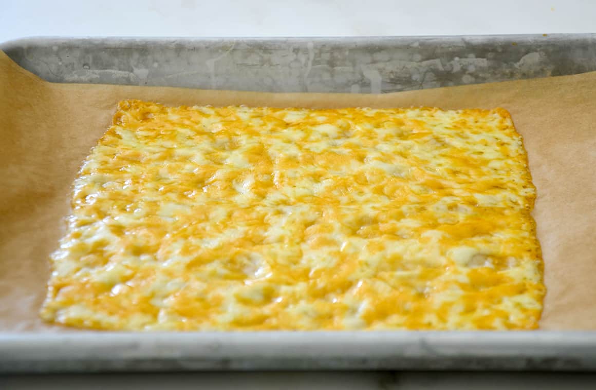 Melted cheese on parchment paper atop a baking sheet