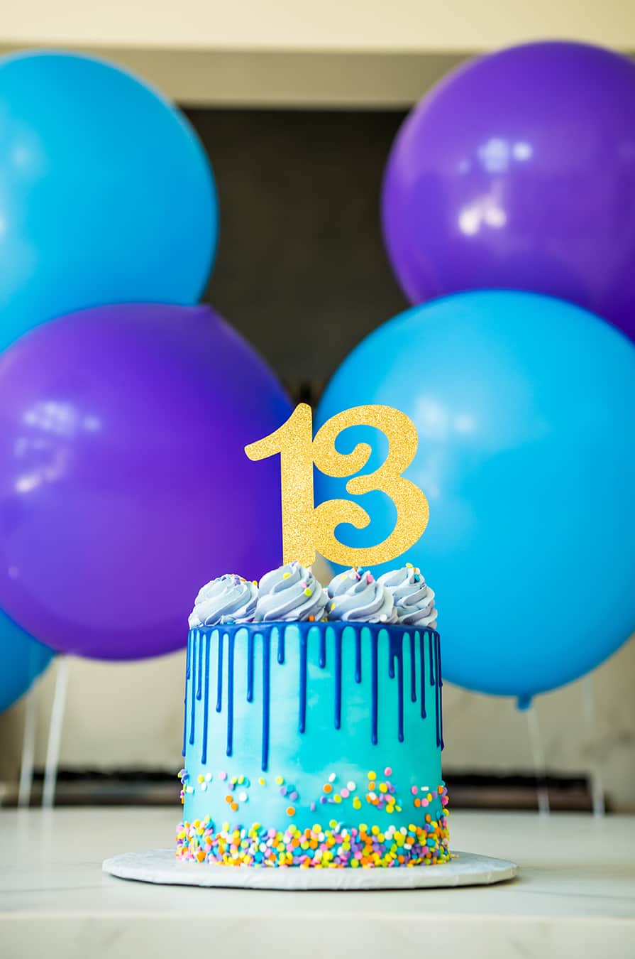 A blue and purple drip cake with sprinkles