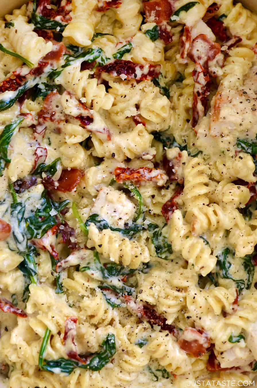 A close-up view of Creamy Tuscan Chicken Pasta with spinach and sun-dried tomatoes