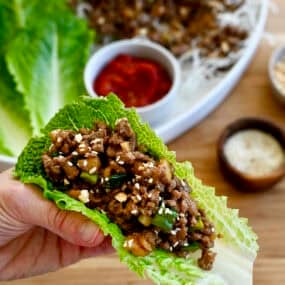 A hand holding a ground chicken lettuce wrap.