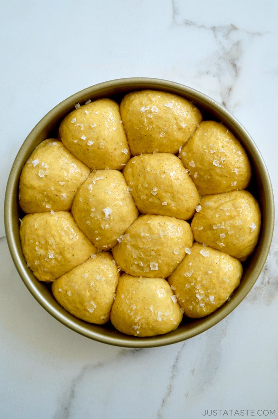 Unbaked dinner rolls in a gold baking pan