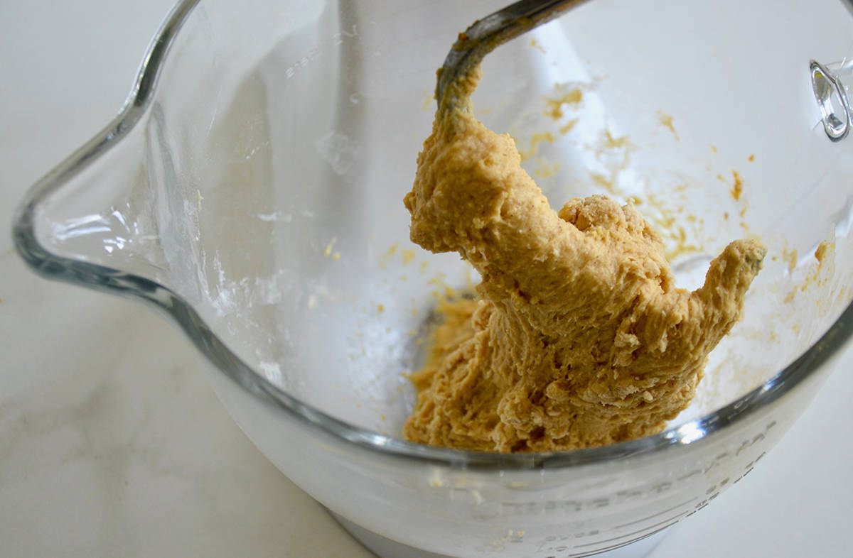 Pumpkin bread dough wrapped around the paddle attachment of a stand mixer.