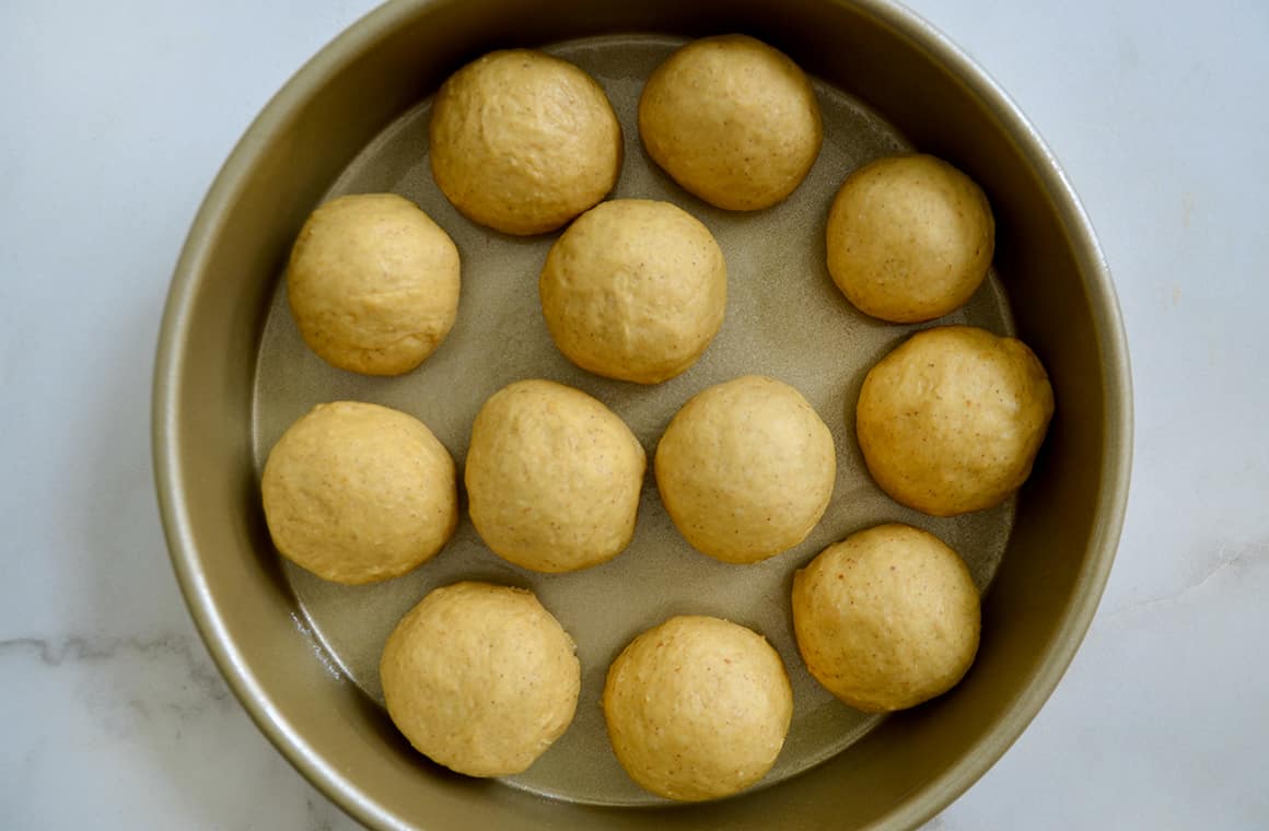 Circles of bread dough in a gold baking pan