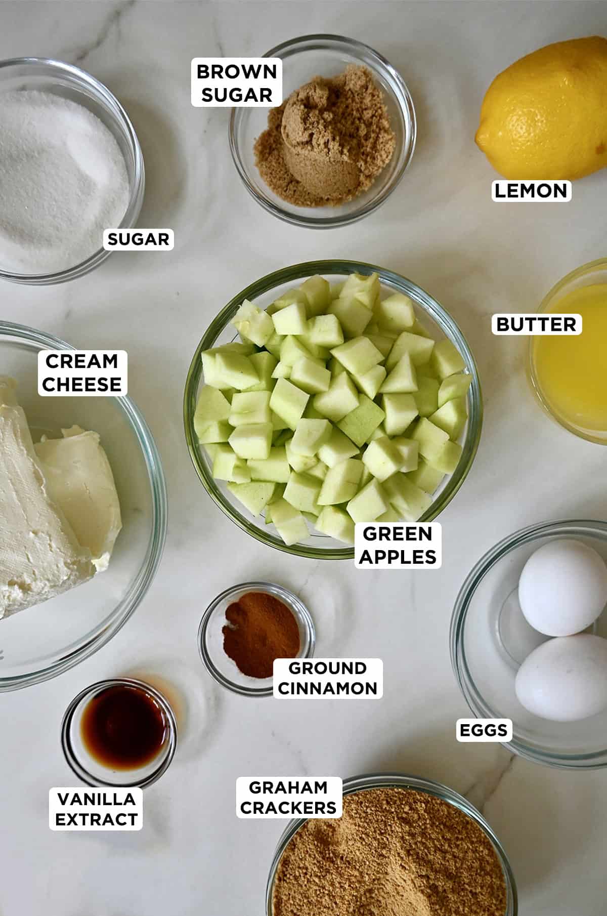 Ingredients for caramel apple cheesecake bars in various prep bowl sizes.