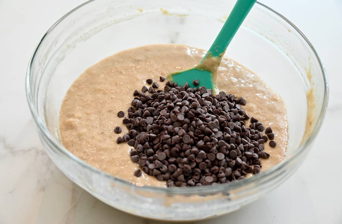 A glass bowl with banana bread batter and chocolate chips