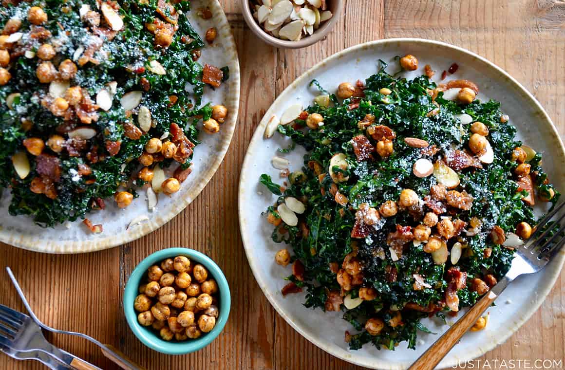 A kale salad on a white plate topped with crispy chickpeas