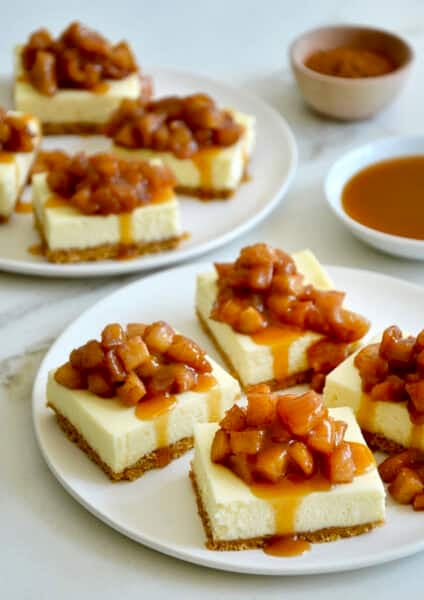 Cheesecake bars topped with a brown sugar apple topping and caramel sauce.
