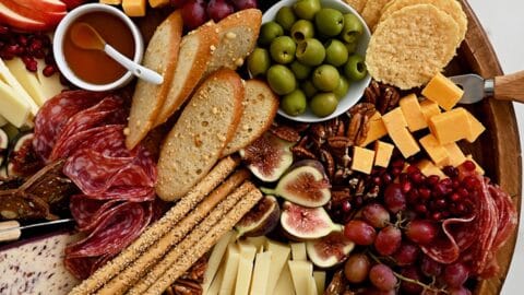 A fall charcuterie board topped with cheese, fruit, salami and olives.