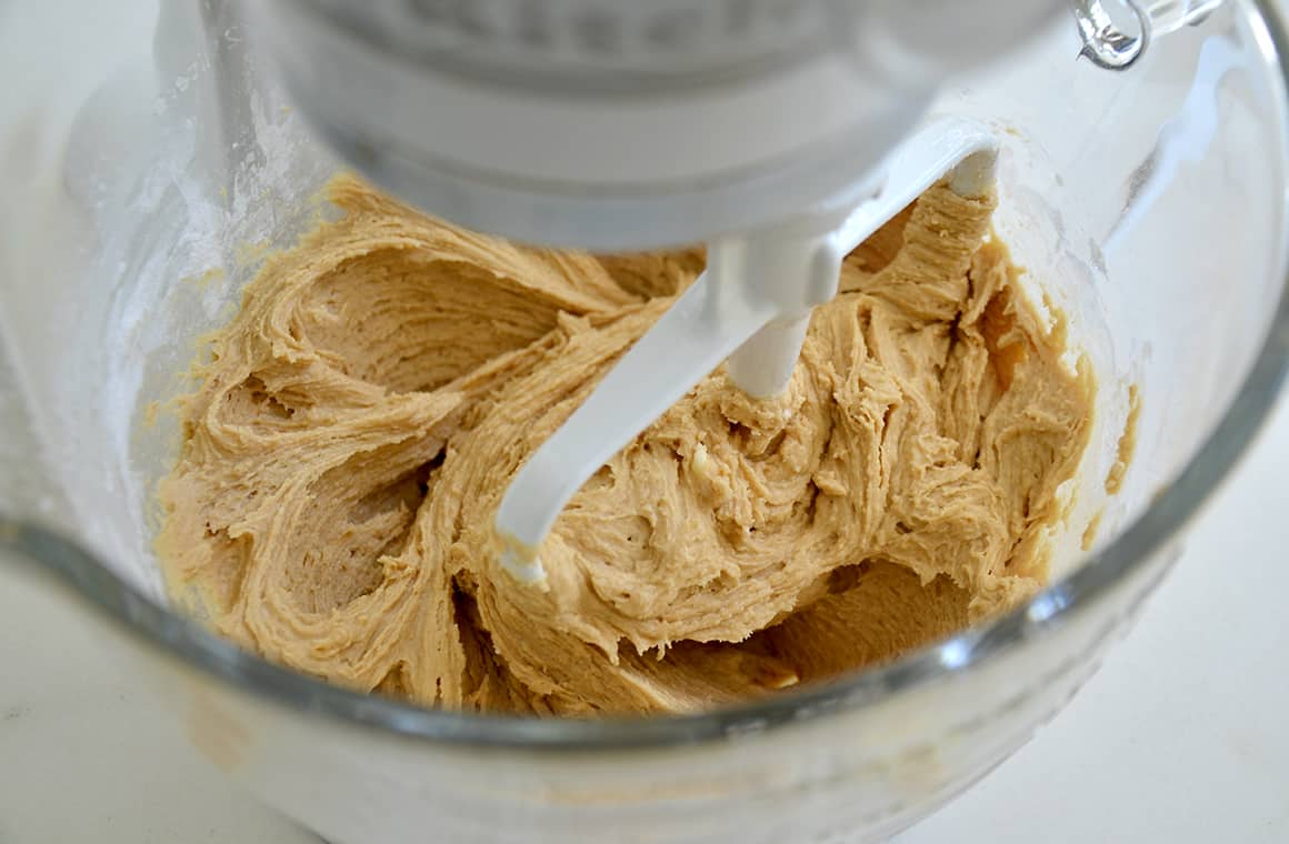 A stand mixer bowl and paddle attachment with cookie dough