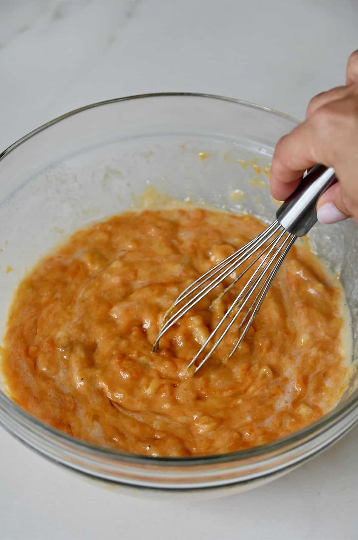 Pumpkin banana bread batter being whisked together in a bowl.