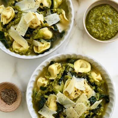 Two bowls containing Quick Tortellini Soup with Greens topped with pesto