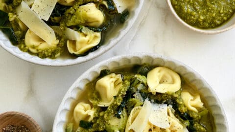 Two bowls containing Quick Tortellini Soup with Greens topped with pesto
