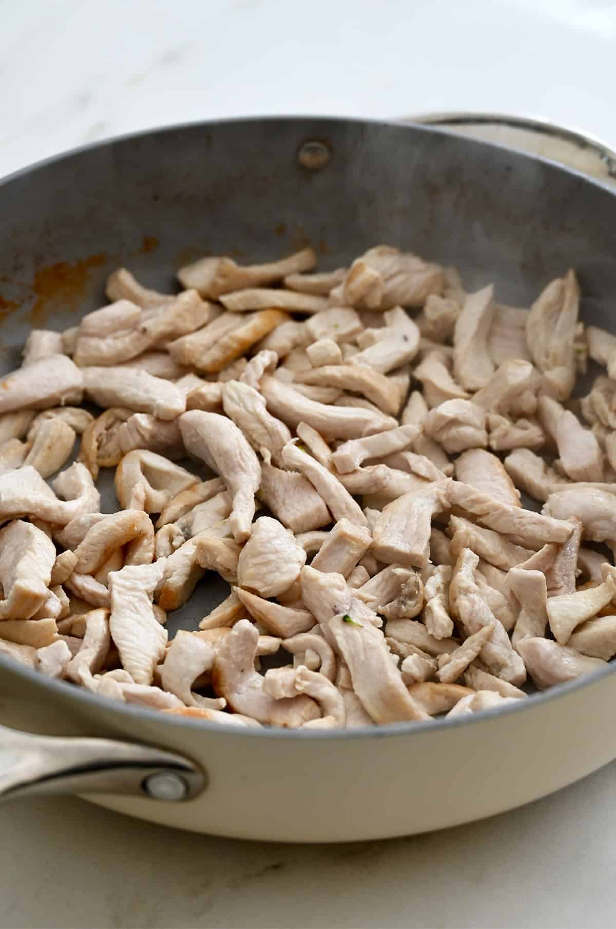 Sautéed sliced chicken in a large skillet.