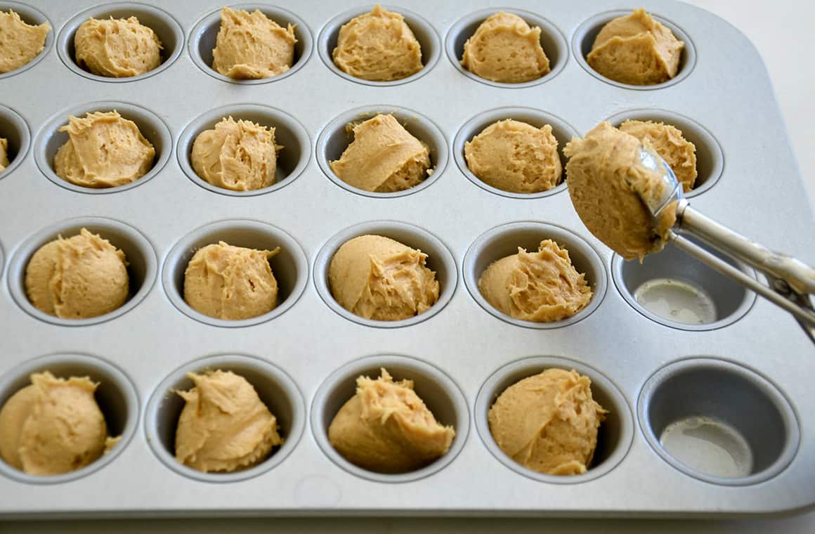 A muffin tin containing scoops of dough