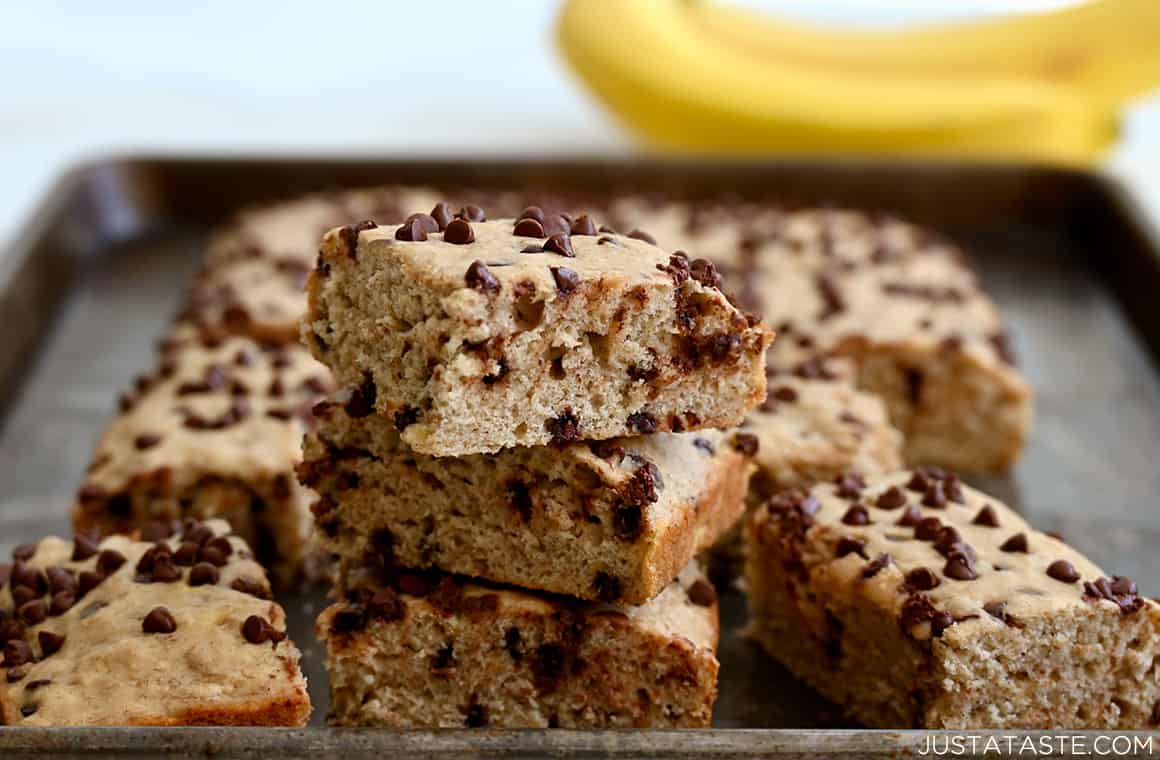 A stack of banana bars with bananas in the background