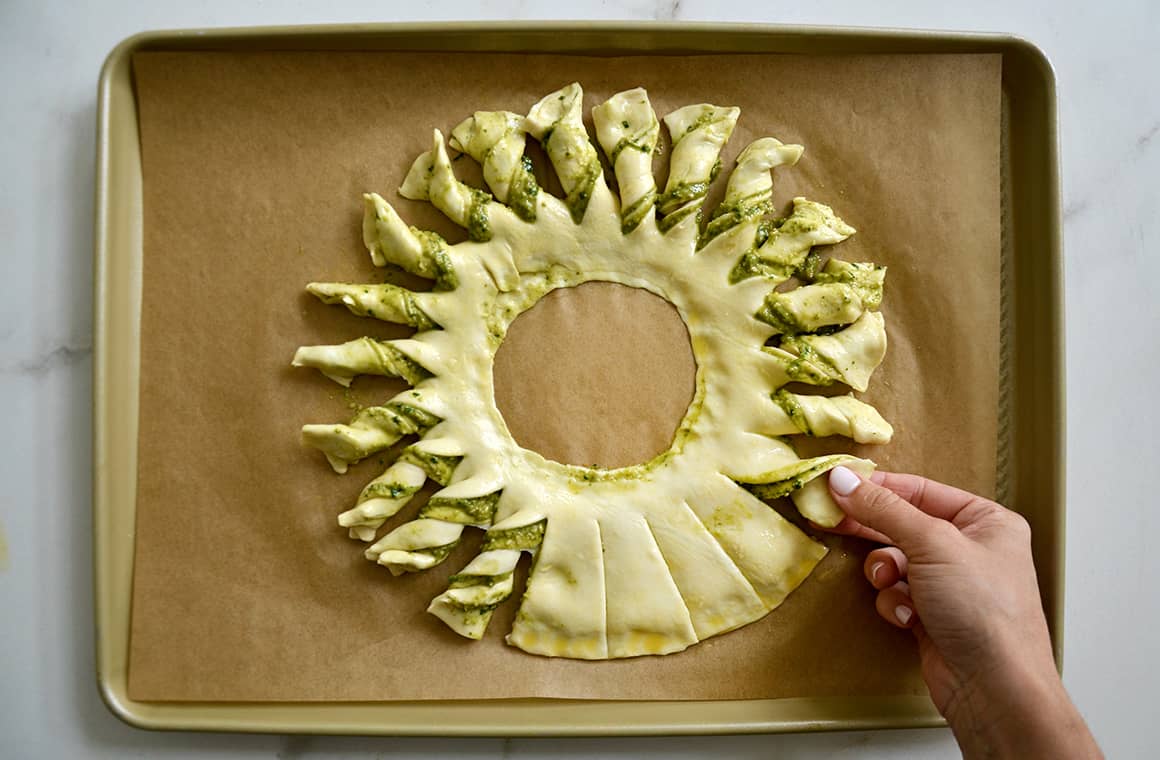 A hand twisting each strip of pastry