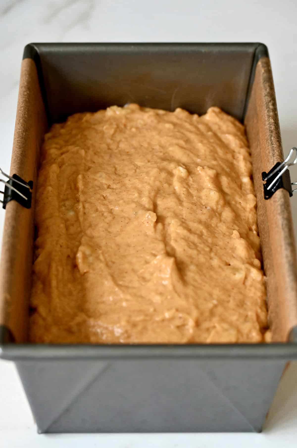 Unbaked pumpkin banana bread in a parchment paper-lined 9-inch bread pan.