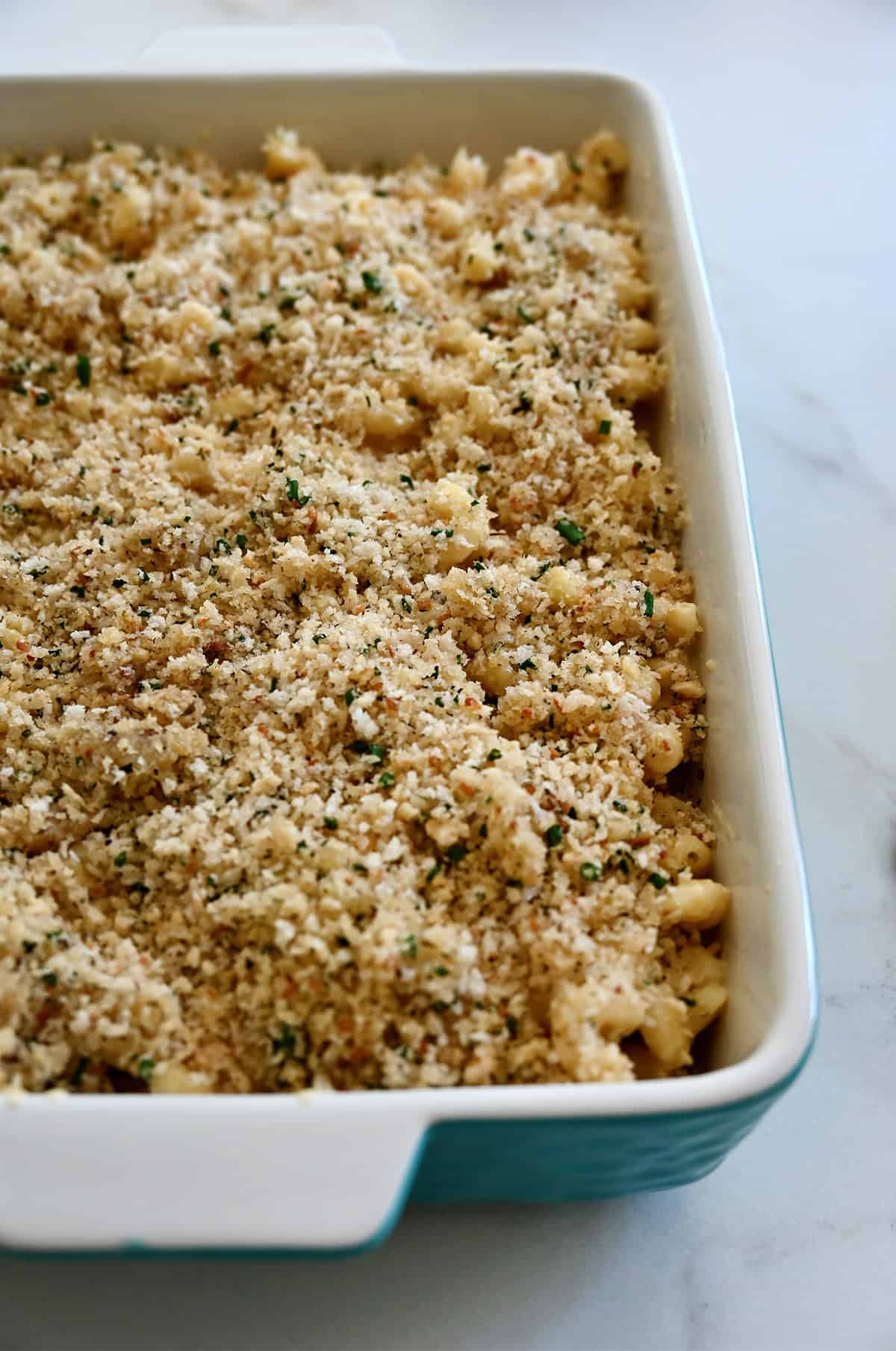 A toasted chive and Panko breadcrumb topping atop mac and cheese in a 9x13 baking dish.