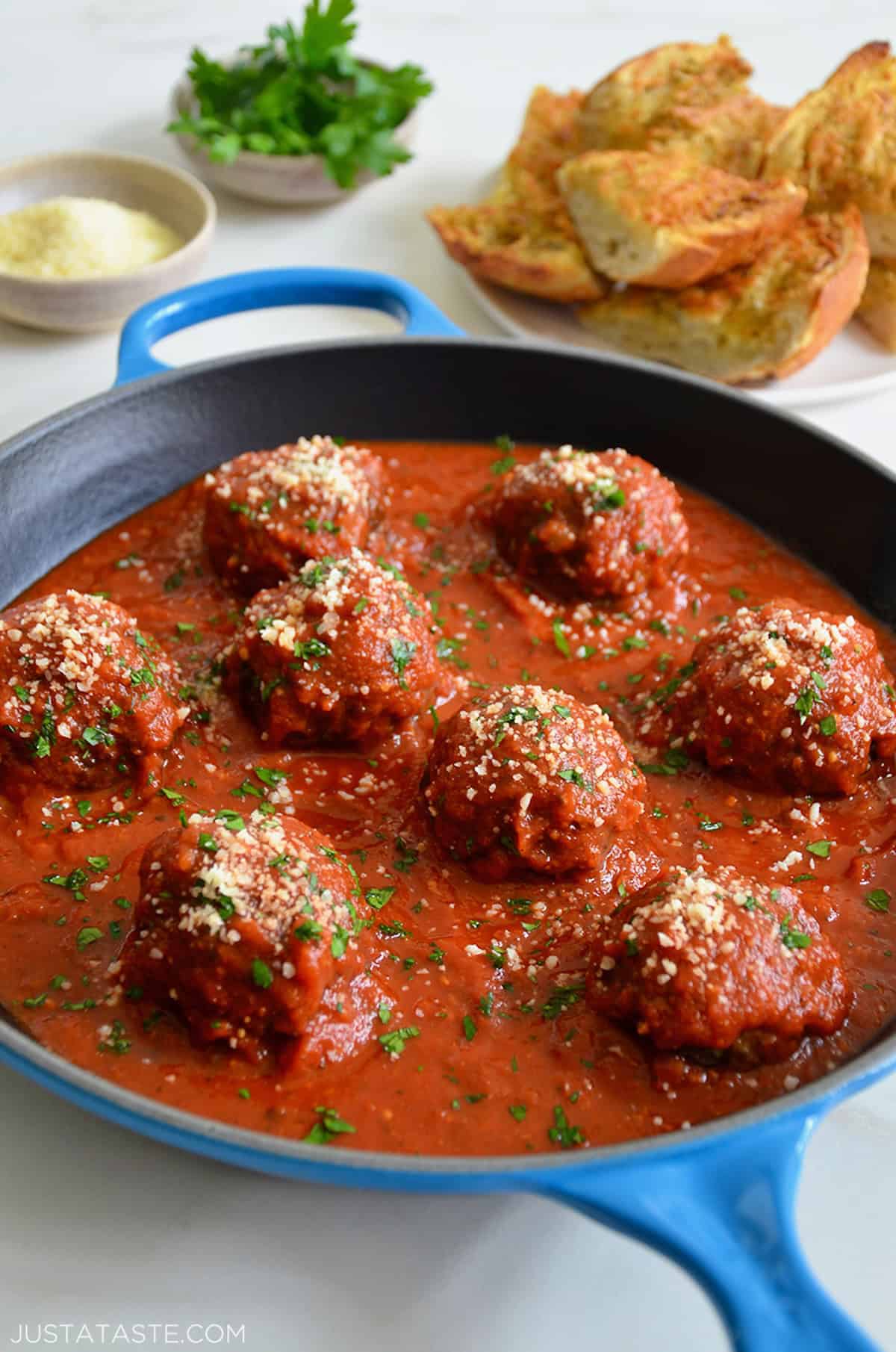 Mozzarella cheese stuffed meatballs simmering in marinara sauce in a skillet.