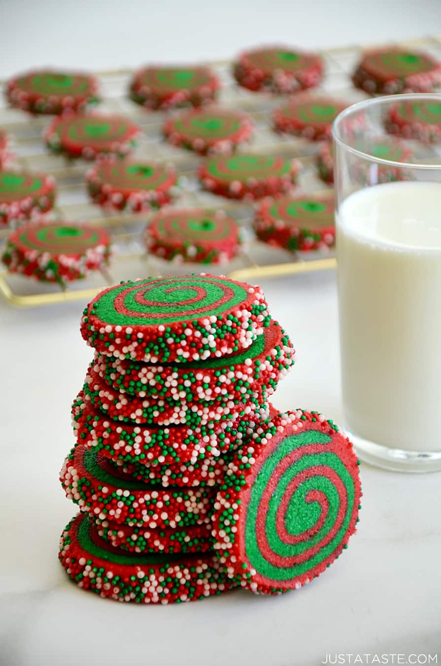 A tall stack of Christmas Pinwheel Cookies next to a glass of milk