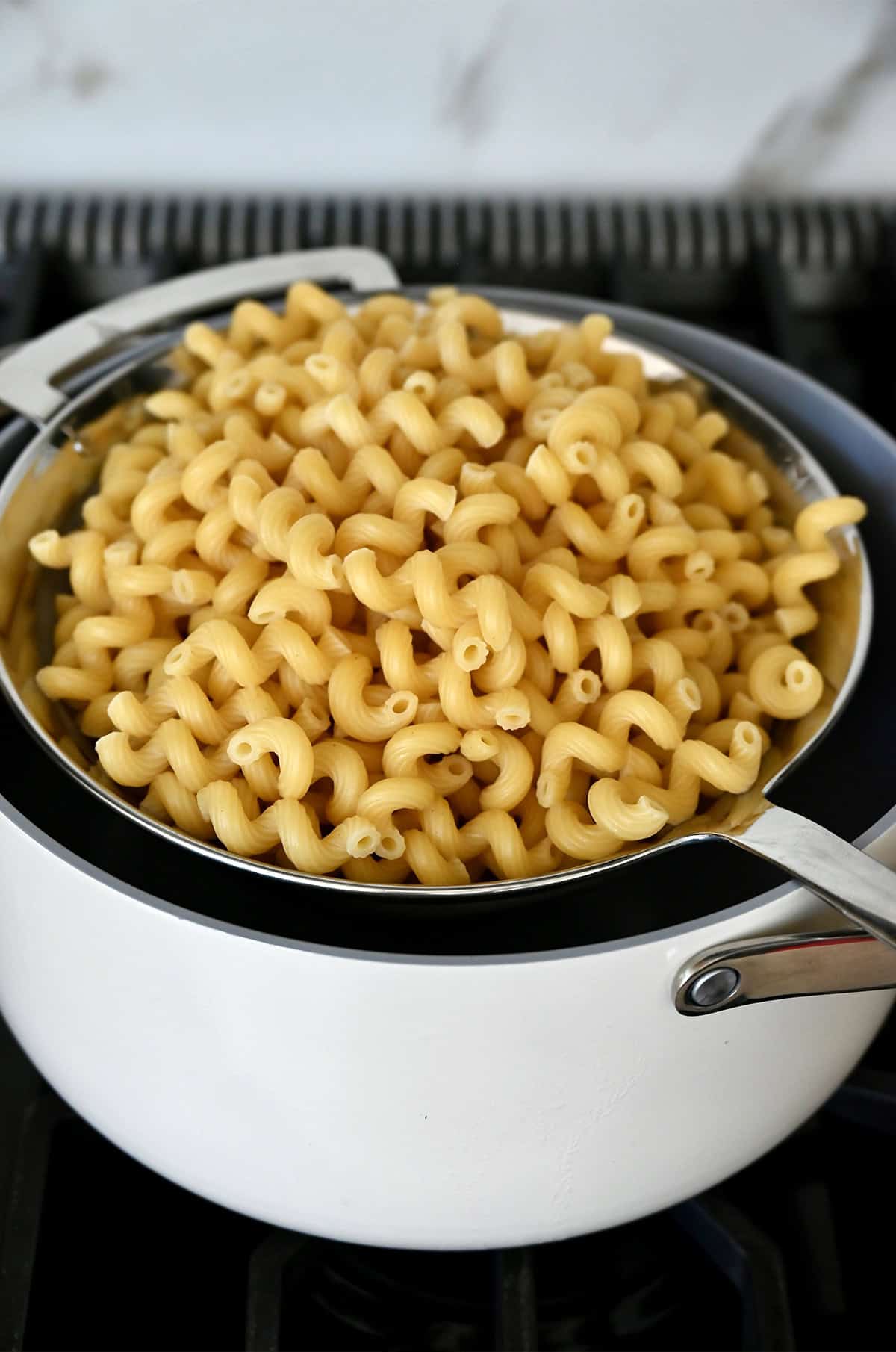 Cooked cavatappi in a mesh strainer over a large stockpot.