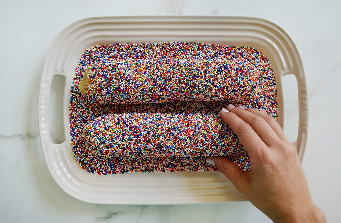 Two cookie dough logs in a dish with rainbow sprinkles