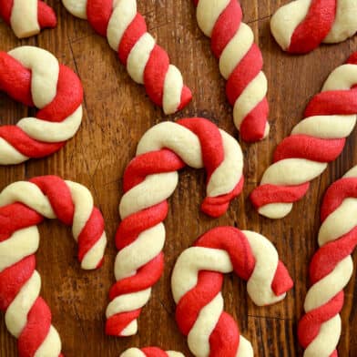 White and red candy cane sugar cookies on a wooden surface.