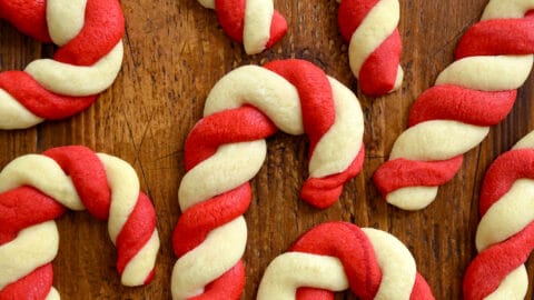 White and red candy cane sugar cookies on a wooden surface.