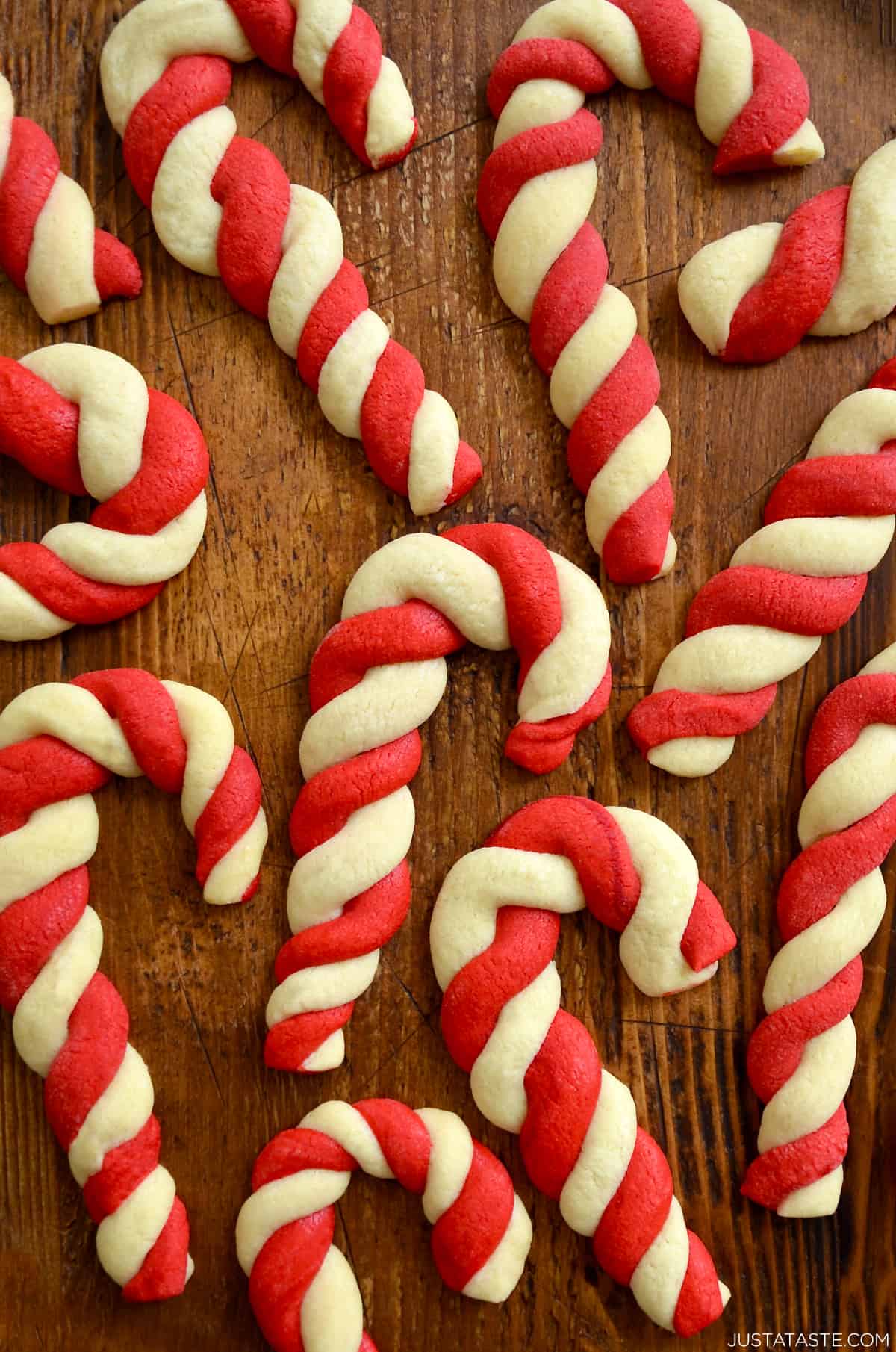 White and red candy cane sugar cookies on a wooden surface.