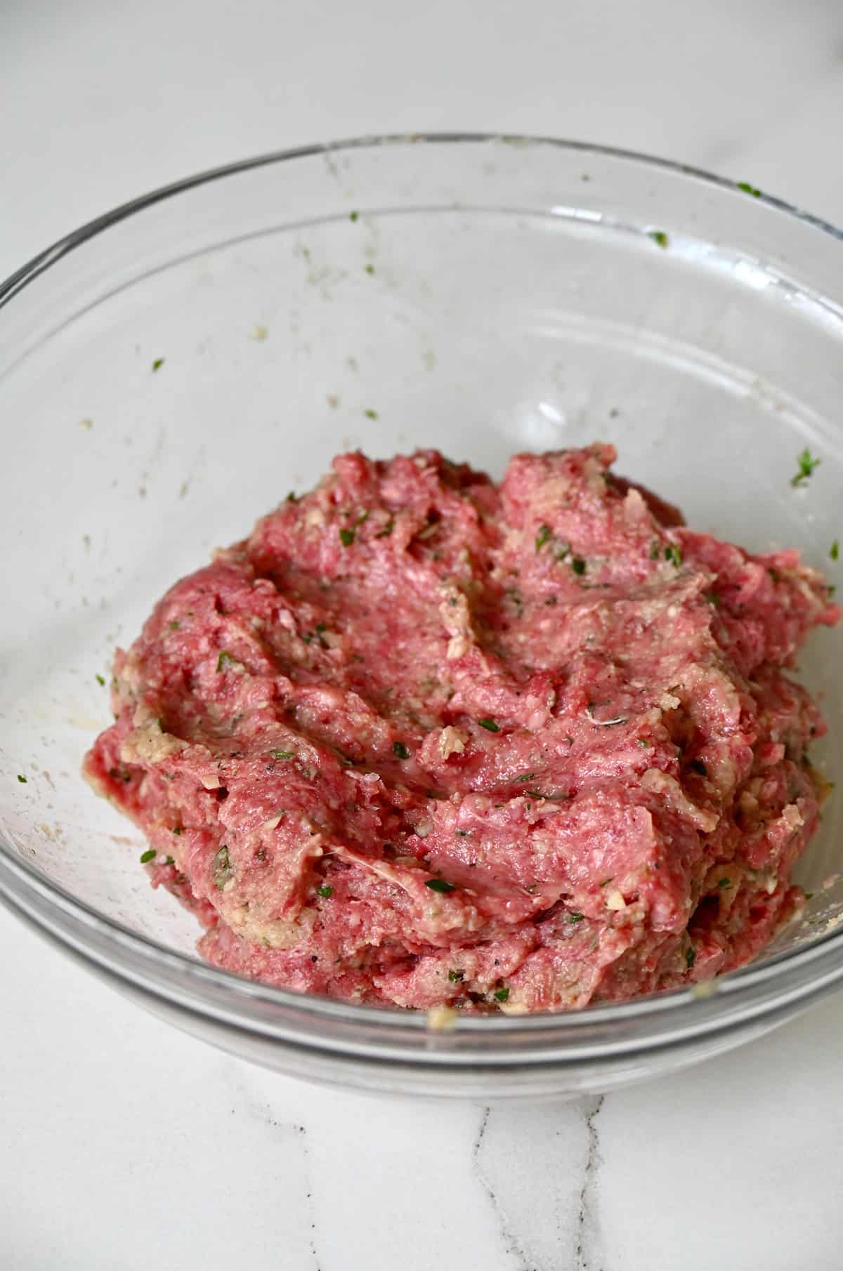 Italian meatball mixture in a glass bowl.