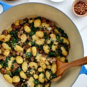 One-Pot Gnocchi with Sausage in a Dutch oven with a wooden spoon