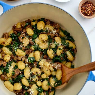 One-Pot Gnocchi with Sausage in a Dutch oven with a wooden spoon