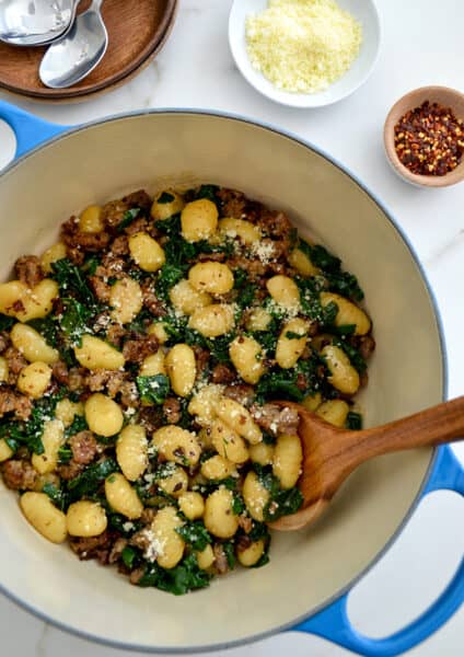 One-Pot Gnocchi with Sausage in a Dutch oven with a wooden spoon