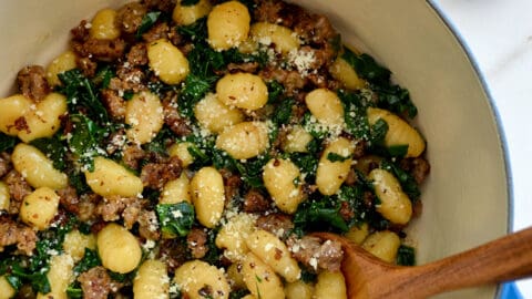 One-Pot Gnocchi with Sausage in a Dutch oven with a wooden spoon