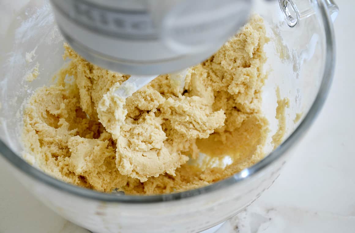 Cookie dough in a stand mixer bowl with a paddle attachment