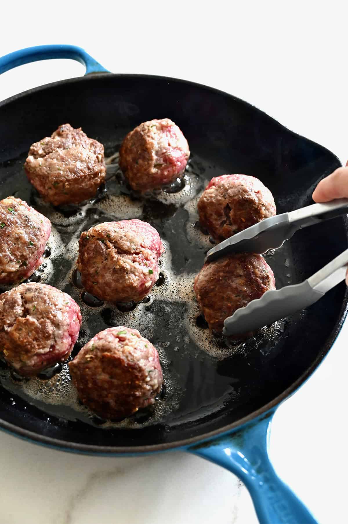 Searing meatballs in an enameled cast iron pan.