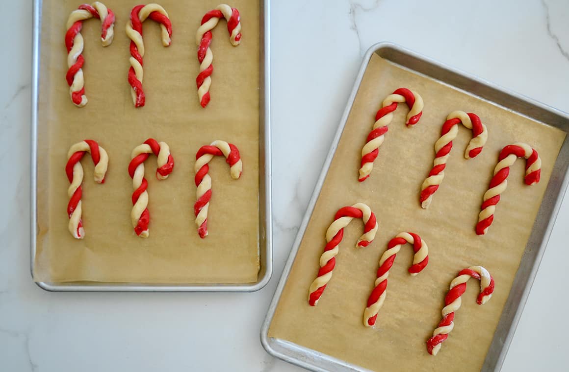 Unbaked Candy Cane Cookies on a parchment paper-lined baking sheet